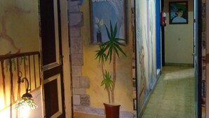 A hallway with a blue ceiling, a wooden bench, a potted plant, and a door leading to another room. - Pensión Sea of Clouds (Las Palmas de Gran Canaria)