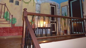 A staircase with a wooden handrail and metal balusters, leading to a room with a blue ceiling and decorative wall murals. - Pensión Sea of Clouds (Las Palmas de Gran Canaria)