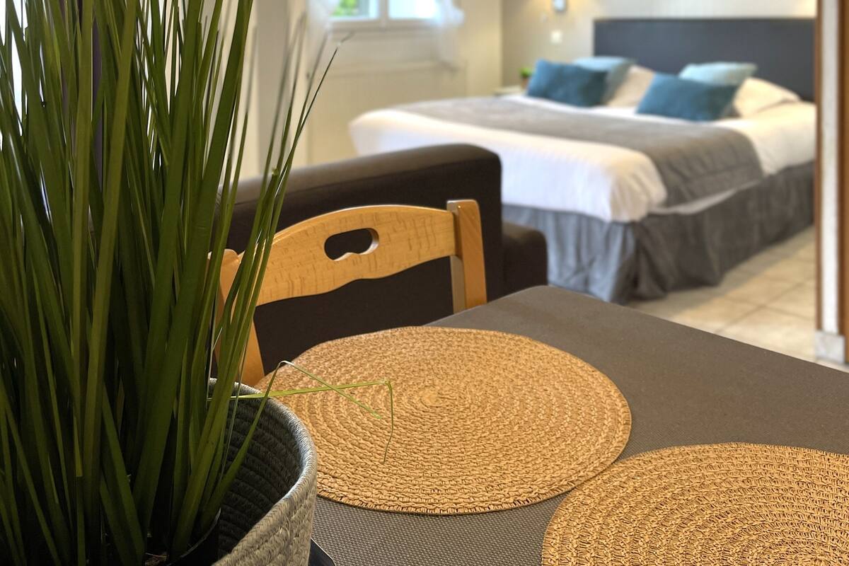A modern bedroom with a bed, bedside table, and a potted plant.