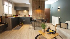 Een moderne keuken met donkere kastjes, een wand bekleed met hout, en een eethoek met een tafel en stoelen.