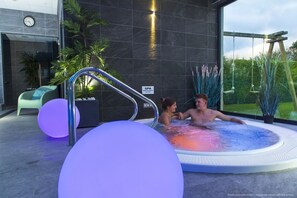 A modern indoor spa area with a hot tub, a clock, and a sign indicating a spa facility. - La Maison Blanche (Sangatte)