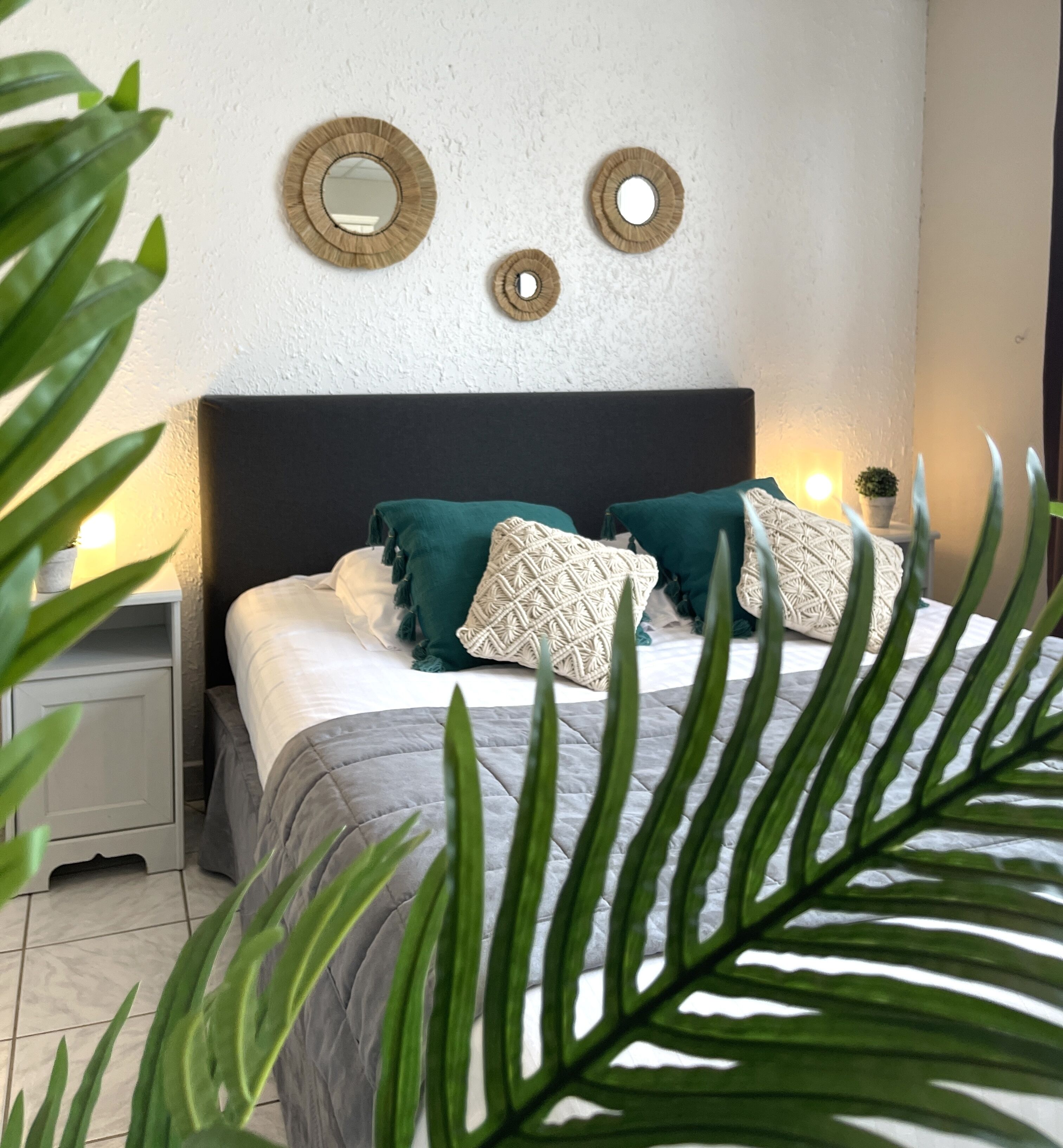 A bedroom with a bed, two bedside tables, a nightstand, and a wall-mounted mirror.