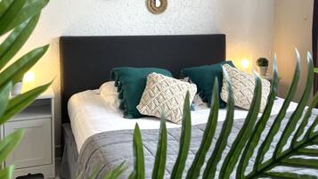 Een slaapkamer met een bed, twee nachtkastjes, een wandspiegel en een nachttafel.