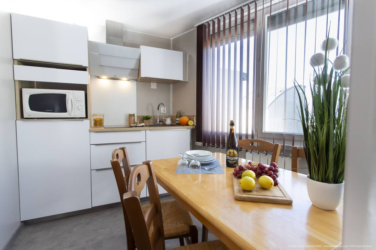 A modern kitchen with white cabinets, a microwave, and a dining area with a wooden table set for two.