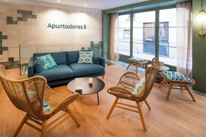 A living room with a sofa, wicker chairs, a coffee table, and a wall with a sign. - Apuntadores 8 (Palma de Mallorca)