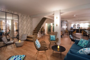 A spacious living area with a staircase, wicker furniture, a blue sofa, and a dining area with chairs and tables. - Apuntadores 8 (Palma de Mallorca)