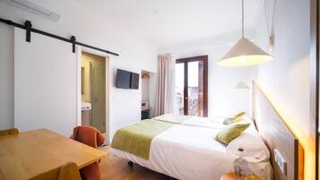 Habitación de hotel con una cama, un escritorio, una silla, un televisor y una ventana.