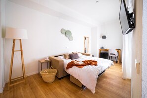 A modern bedroom with a bed, bedside table, lamp, and a desk with a chair. - Apuntadores 8 (Palma de Mallorca)