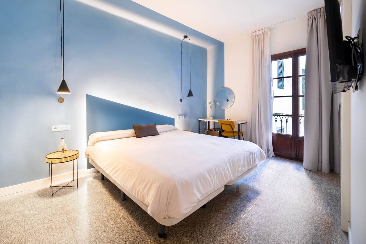 Un dormitorio con cama, mesitas de noche, un escritorio y una silla.