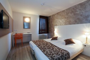 Relax in a stylish room with a neatly made bed, desk, and flat-screen TV.