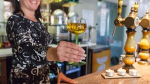 A person holding a glass of wine at a bar with a tap and candles. - The Originals City, Hotel Mulhouse, Ile Napoleon (Rixheim)