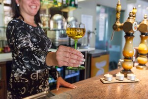 Una persona sosteniendo una copa de vino en un bar con grifo y velas.