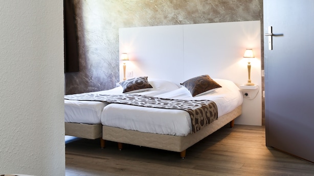 A modern bedroom with a large bed, two bedside lamps, and a textured wall. - The Originals City, Hotel Mulhouse, Ile Napoleon (Rixheim)