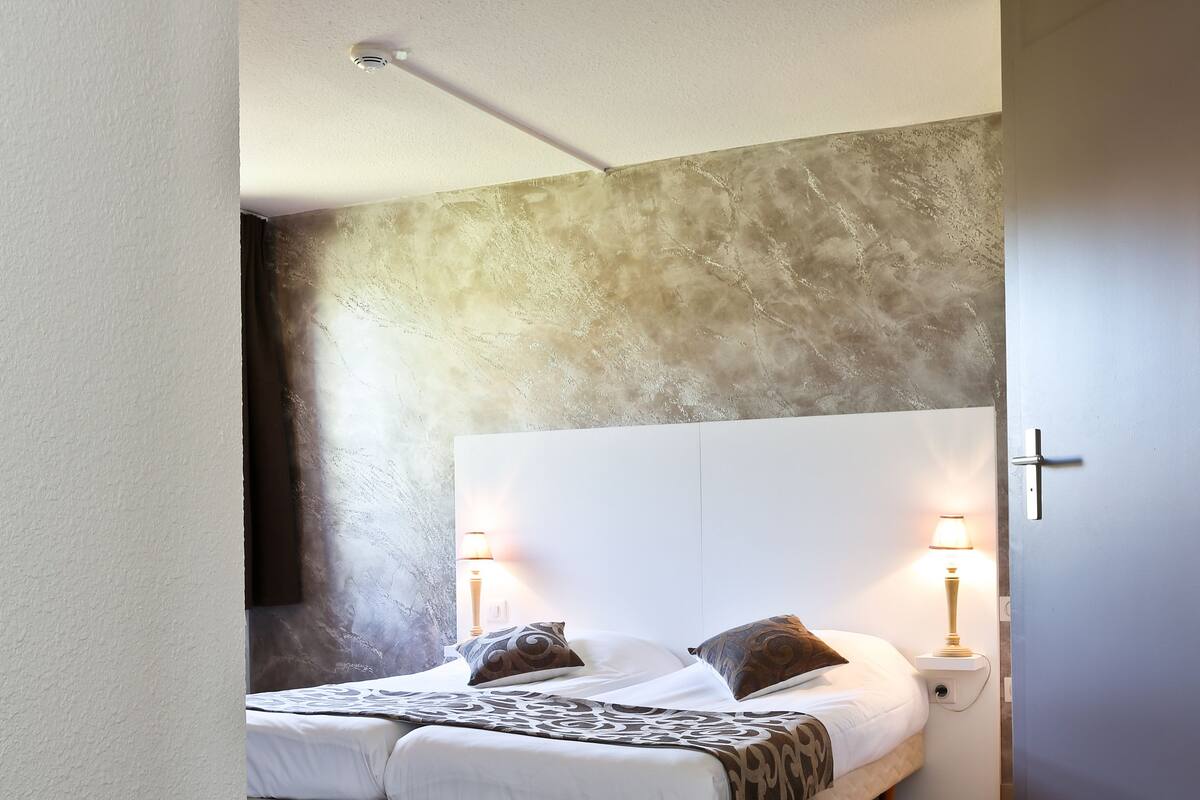 A modern bedroom with a large bed, two bedside lamps, and a textured wall.
