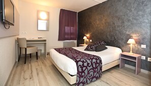 Relax in comfort with a large bed, desk, and TV, plus two bedside lamps and a large mirror.