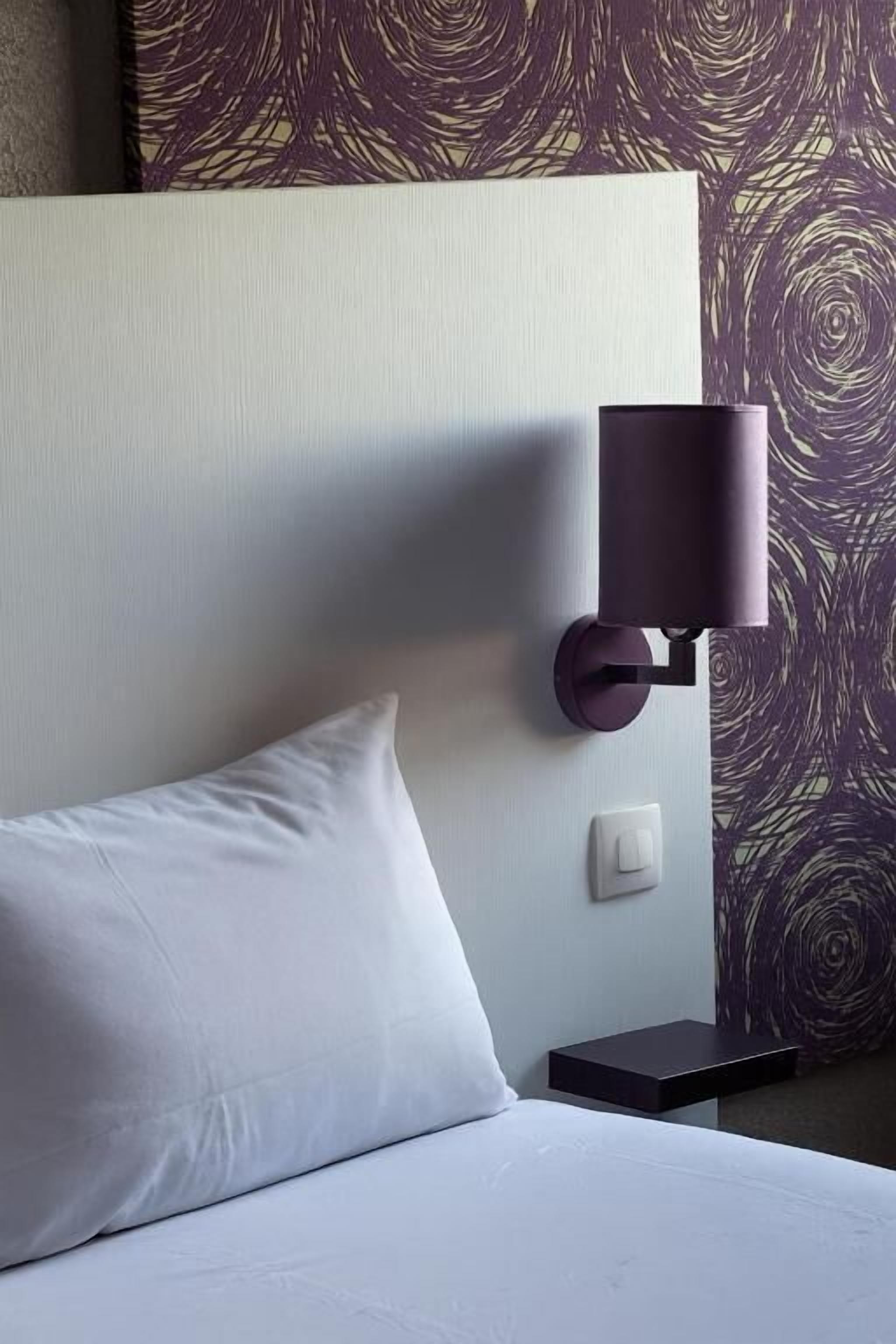 Ein Hotelzimmer mit einem Bett, einer Wandlampe und einer Steckdose.