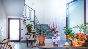 A dining area with a wooden table, chairs, potted plants, and a staircase in the background. - Due Platani (Airuno)