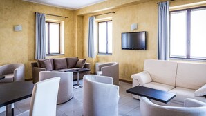 A modern living room with a sofa, armchairs, a coffee table, and a flat-screen TV mounted on the wall. - Due Platani (Airuno)