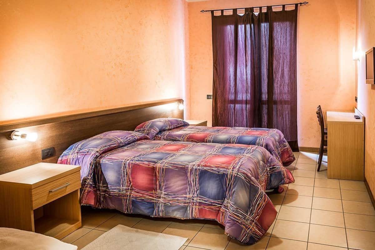 Un dormitorio con dos camas, una mesita de noche de madera, un escritorio y una silla.