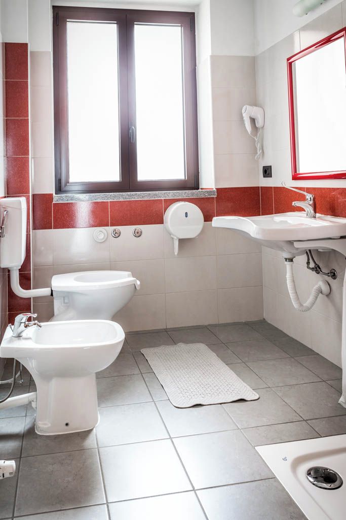 Une salle de bain comprenant des toilettes, un bidet, un lavabo et une fenêtre.