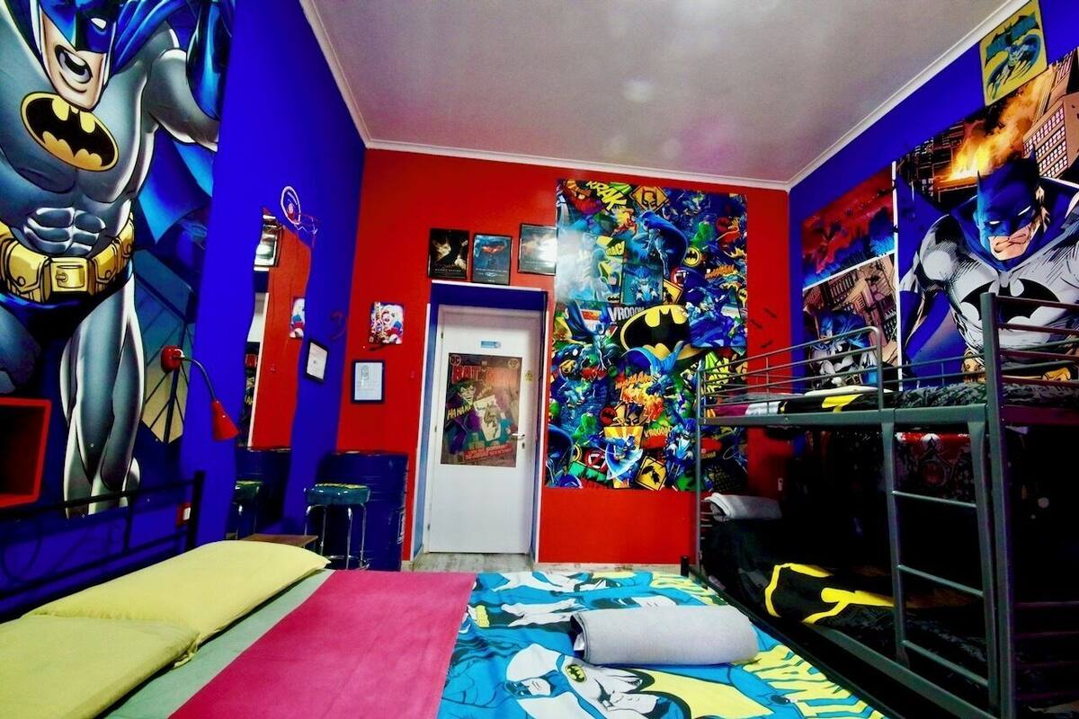 A room with a bunk bed, a large Batman poster, and a colorful superhero-themed wall.