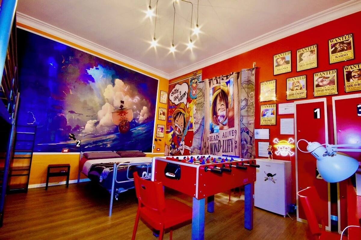 A room with a foosball table, posters on the wall, and a large window with a view of the sky.