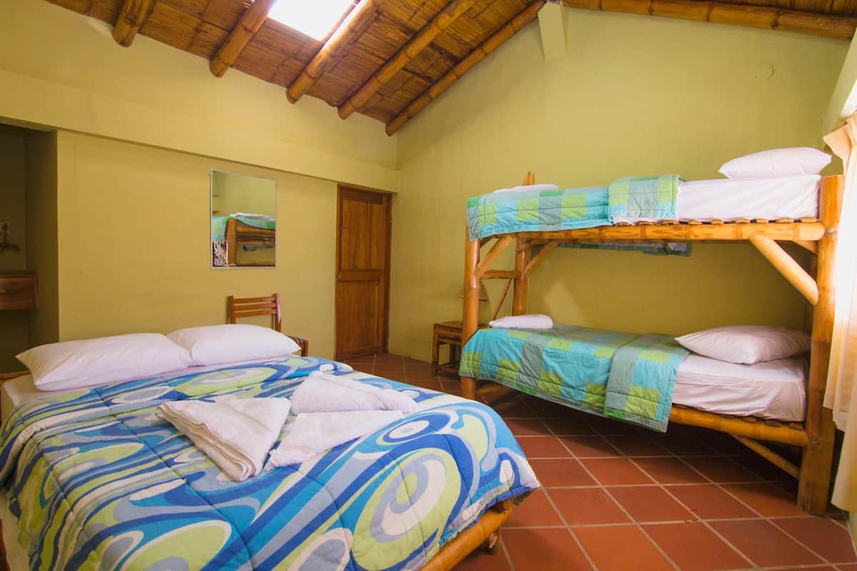 Ein Zimmer mit zwei Etagenbetten, Holzboden, gefliestem Boden, einer Holztür und einem Spiegel an der Wand.