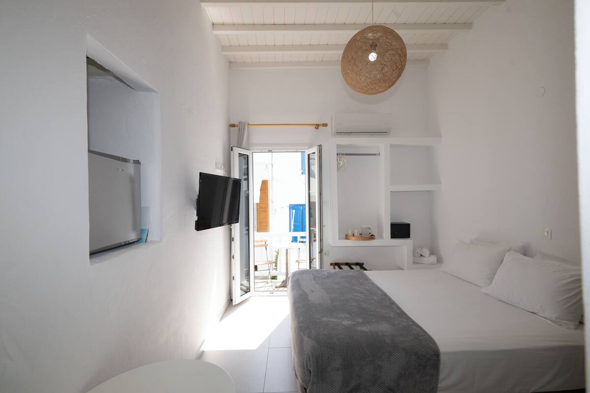 A bedroom with a bed, a television, a wardrobe, and a window.