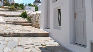 Un edificio blanco con balcón, escalones de piedra y una puerta.