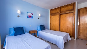 Quarto com duas camas, um guarda-roupa de madeira e um quadro na parede.