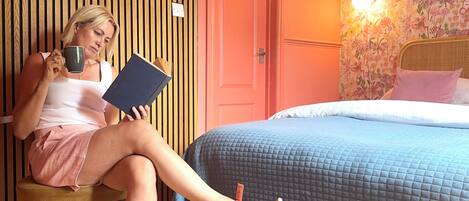 A room with a bed, a chair, a wall-mounted picture, and a door.