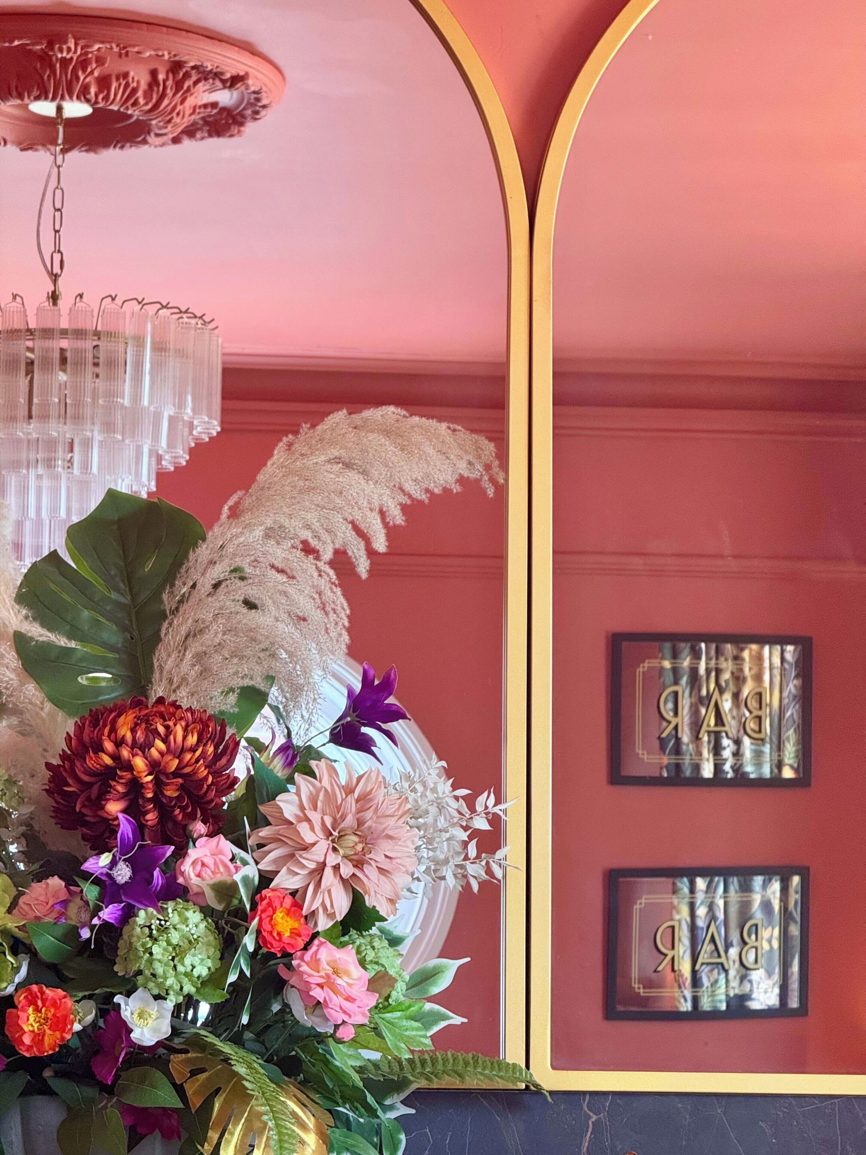 Una habitació amb un candelabrum, un arranjament floral i dos quadres penjats a la paret.