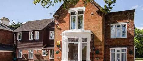 A two-story brick house with a bay window and a small porch.