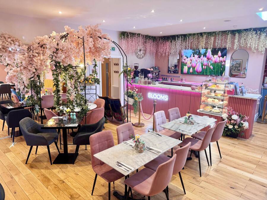 Um restaurante com decorações florais rosa, um balcão com um letreiro de neon e uma parede com uma pintura floral.