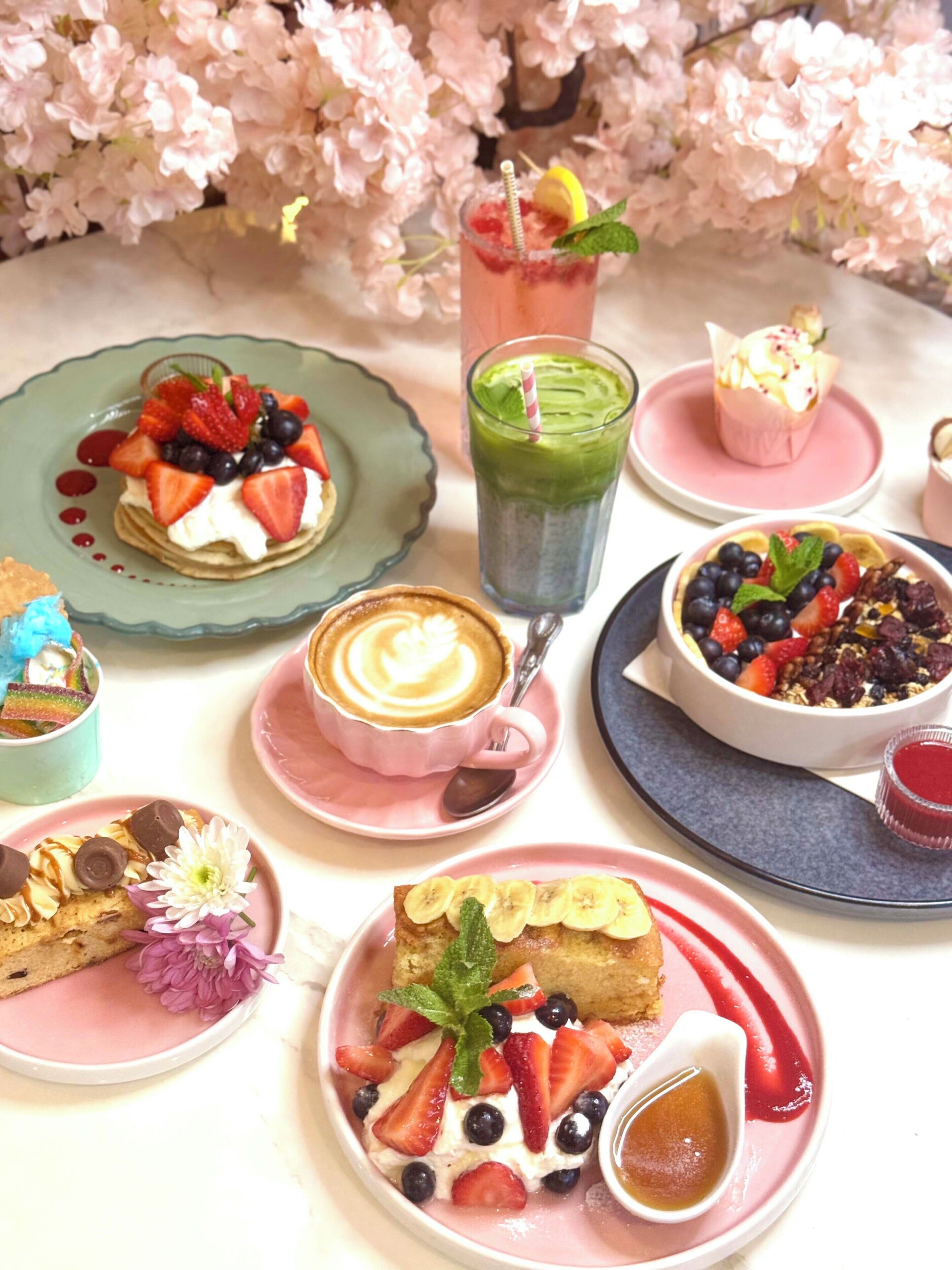 A variety of desserts and beverages on a table with a cherry blossom backdrop.