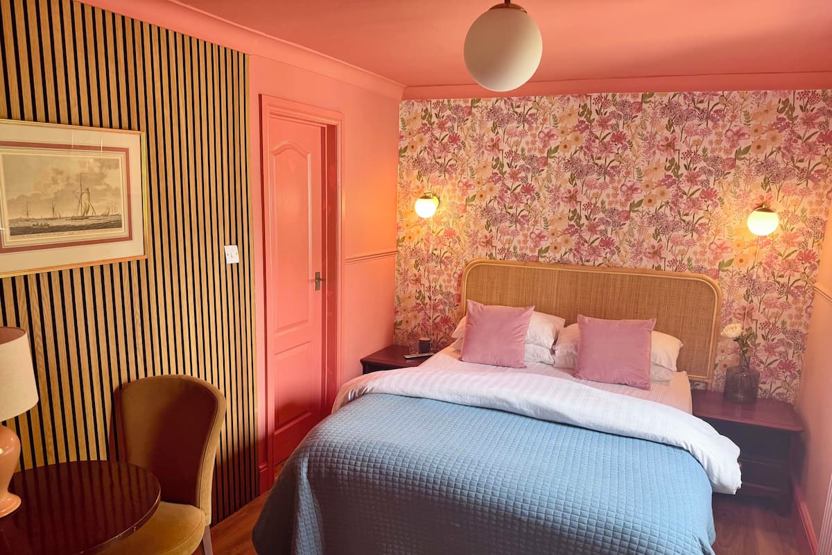 A bedroom with a bed, a chair, a table, and a door.