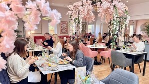 Un restaurante con mesas preparadas para comer, rodeado de decoración floral rosa.