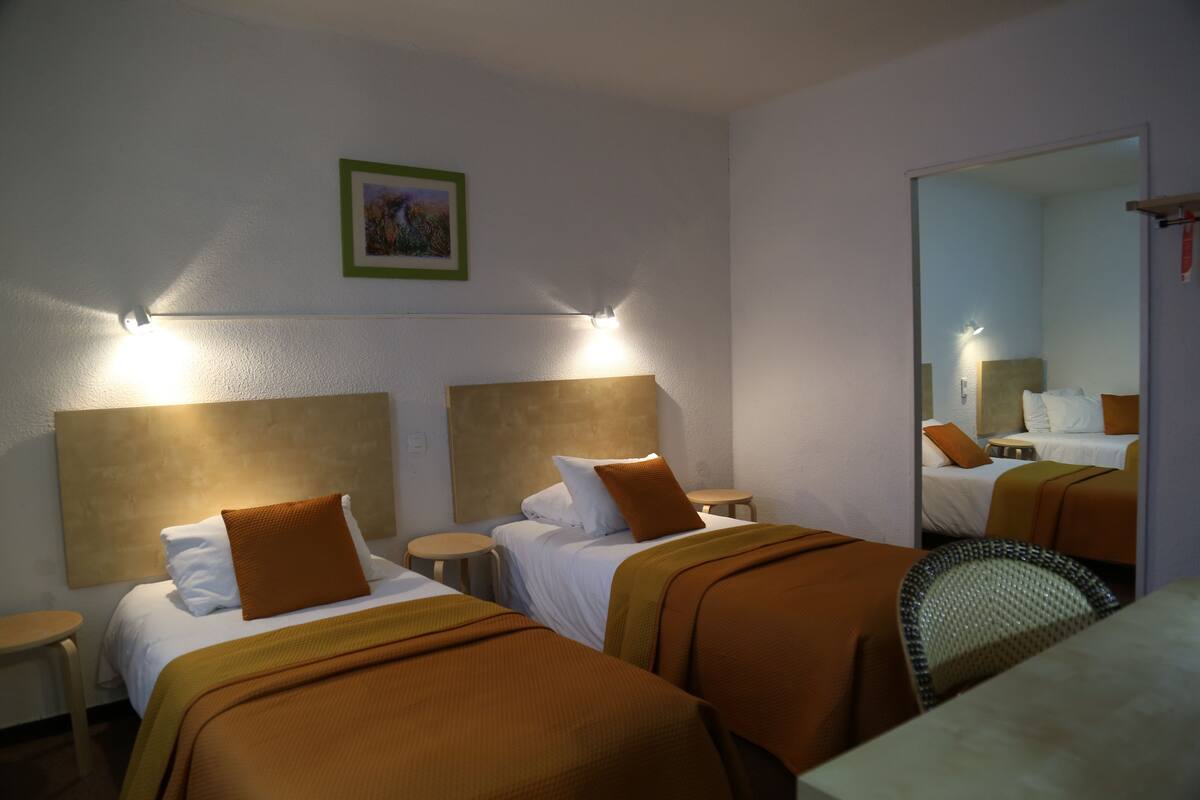 A hotel room with two beds, a round table, and a chair.