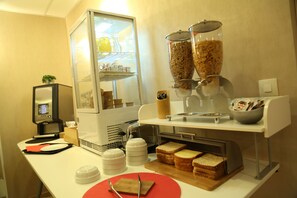 A breakfast station with a coffee machine, cereal dispensers, and bread. - Hôtel Concorde Béziers (Béziers)