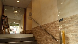 Una escalera con barandilla, una pared con diseño de piedra y un cartel que dice 'CONCORDE'.
