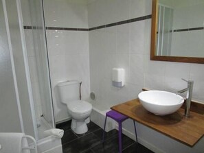 A bathroom with a white toilet, a sink with a wooden countertop, and a mirror above the sink. - Hôtel Concorde Béziers (Béziers)