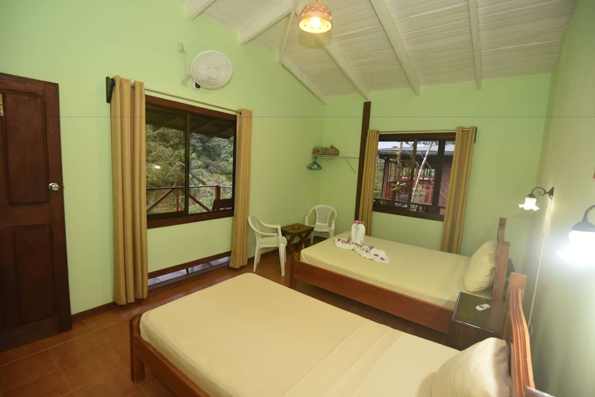 Una habitación con una cama, una silla, una mesita y una ventana con cortinas.