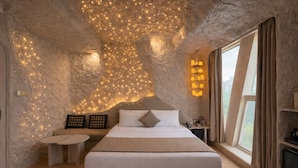 Une chambre à coucher avec un grand lit, une petite table, une table de chevet et une fenêtre avec des rideaux.