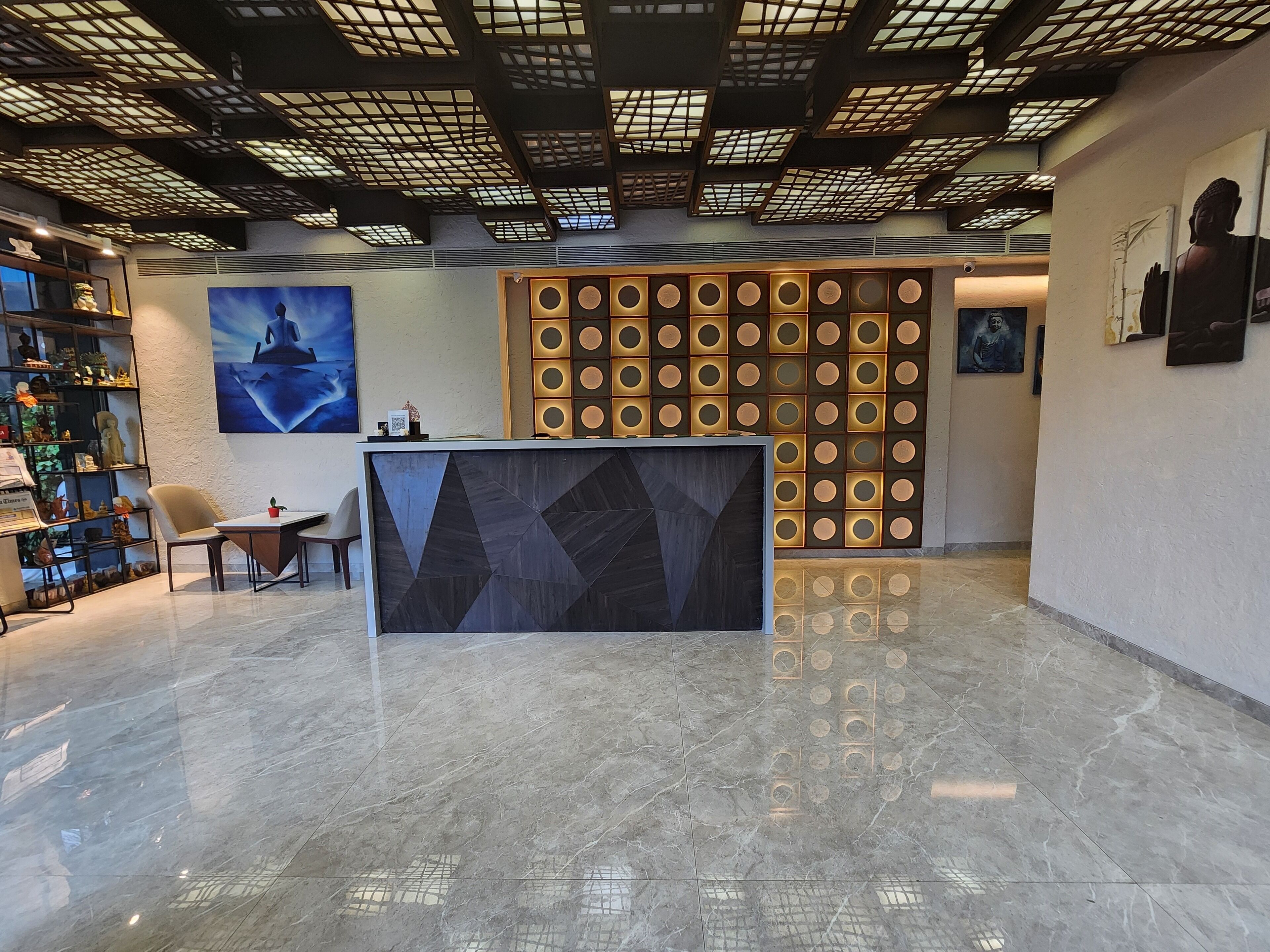 Un área de recepción con piso de mármol, un mostrador de recepción y una pared con diseños circulares.