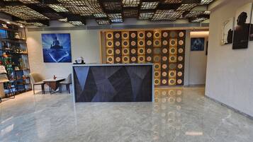 Un área de recepción con piso de mármol, un mostrador de recepción y una pared con diseños circulares.