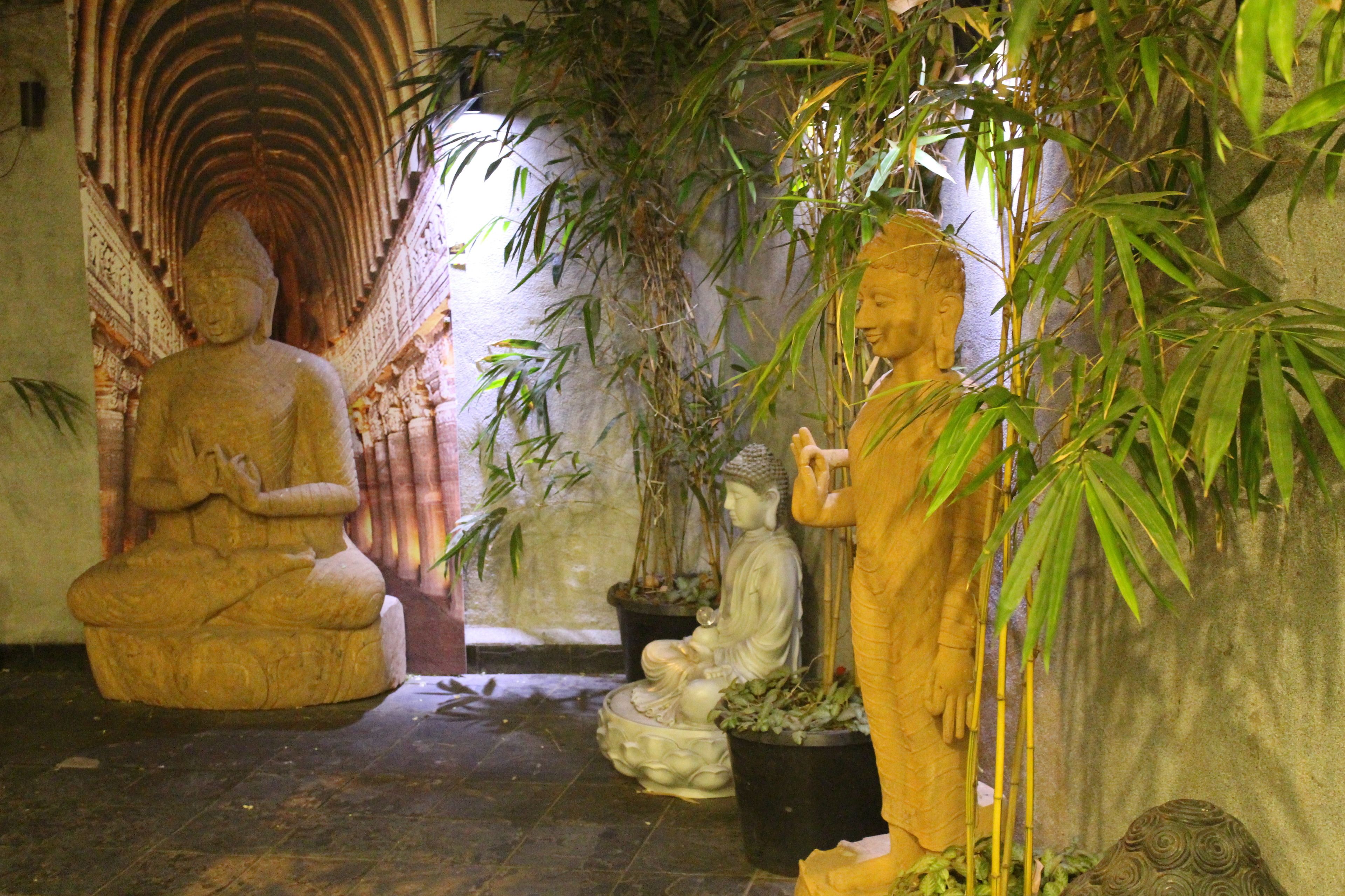 A serene indoor garden with stone statues and lush greenery.