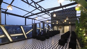 Un salon sur le toit doté d’un sol à motifs géométriques, d’un éclairage moderne et offrant une vue sur le paysage urbain.