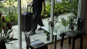 A room with a glass table and chairs, a potted plant, and a suitcase on the floor. - Nantra Silom (Bangkok)
