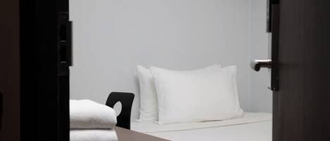 A hotel room with a bed, a chair, and a table with towels.