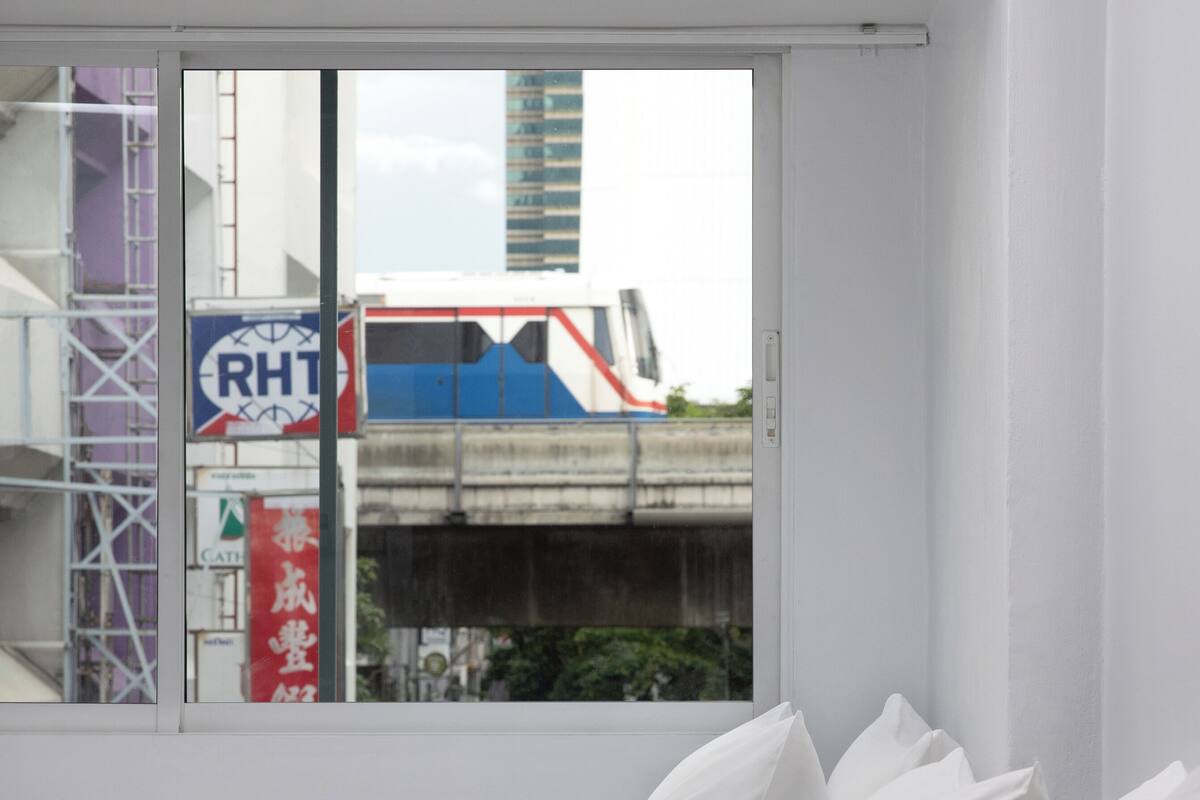 Ein weißes Sofa mit Kissen in einem Raum mit einem großen Fenster.
